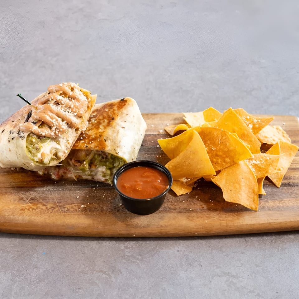 Grilled burrito with sauce and cheese, served with tortilla chips and salsa on a wooden board.